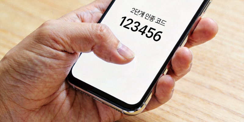 스마트폰에서 2단계 인증 코드를 확인하는 사용자의 손 이미지